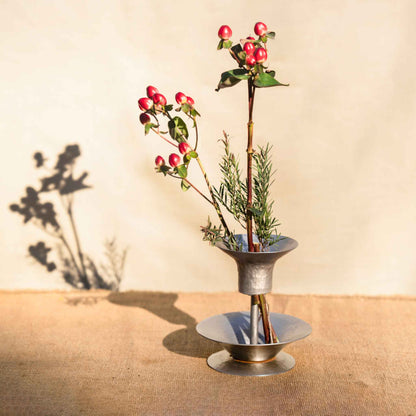 An arrangement using the collective hammered metal stem vase and bouquet ringson a wooden table and neutral background
