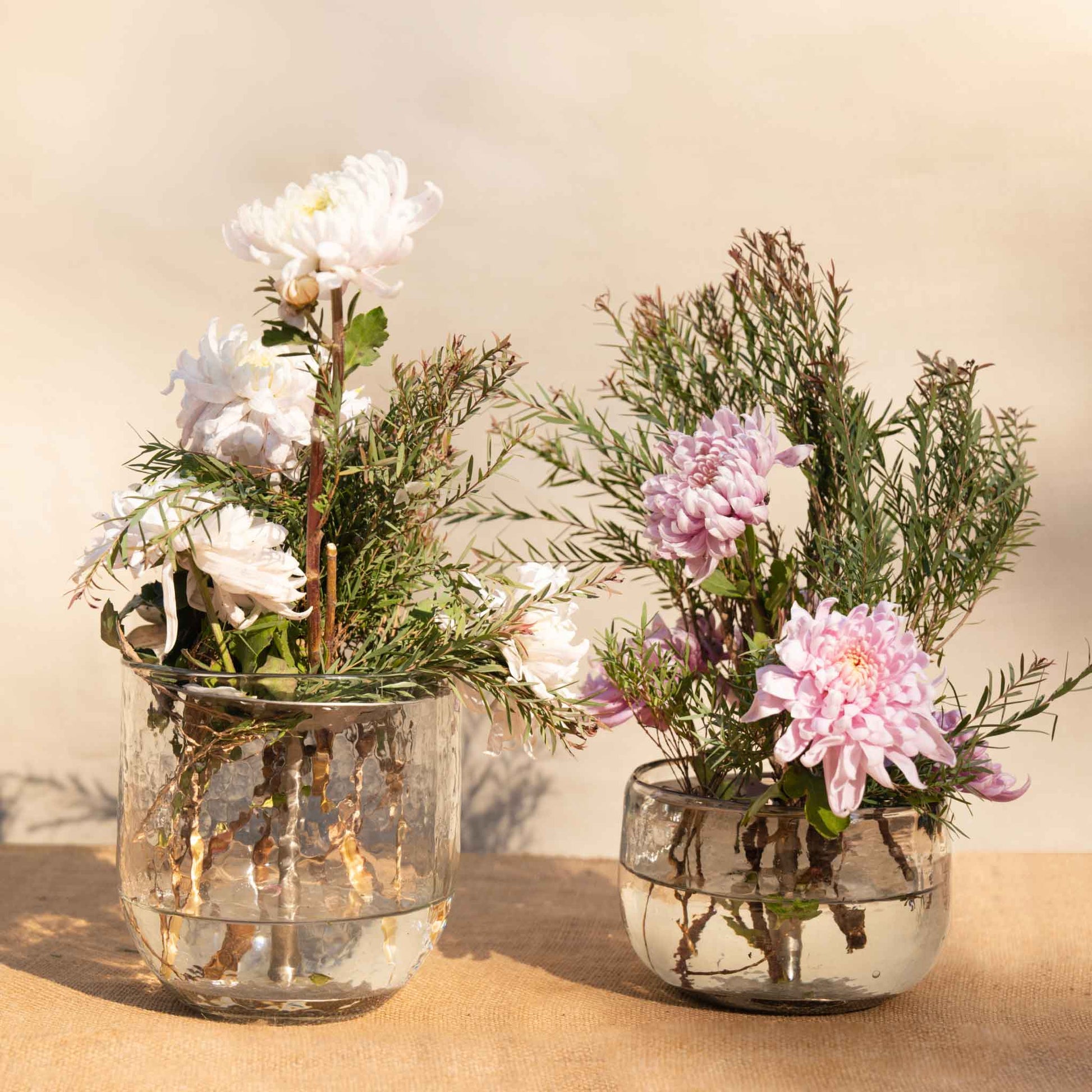 A floral bouquet using the collective pebbled vase and flower frog on a neutral background