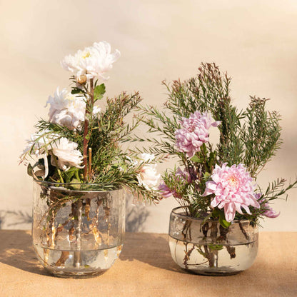 A floral bouquet using the collective pebbled vase and flower frog on a neutral background