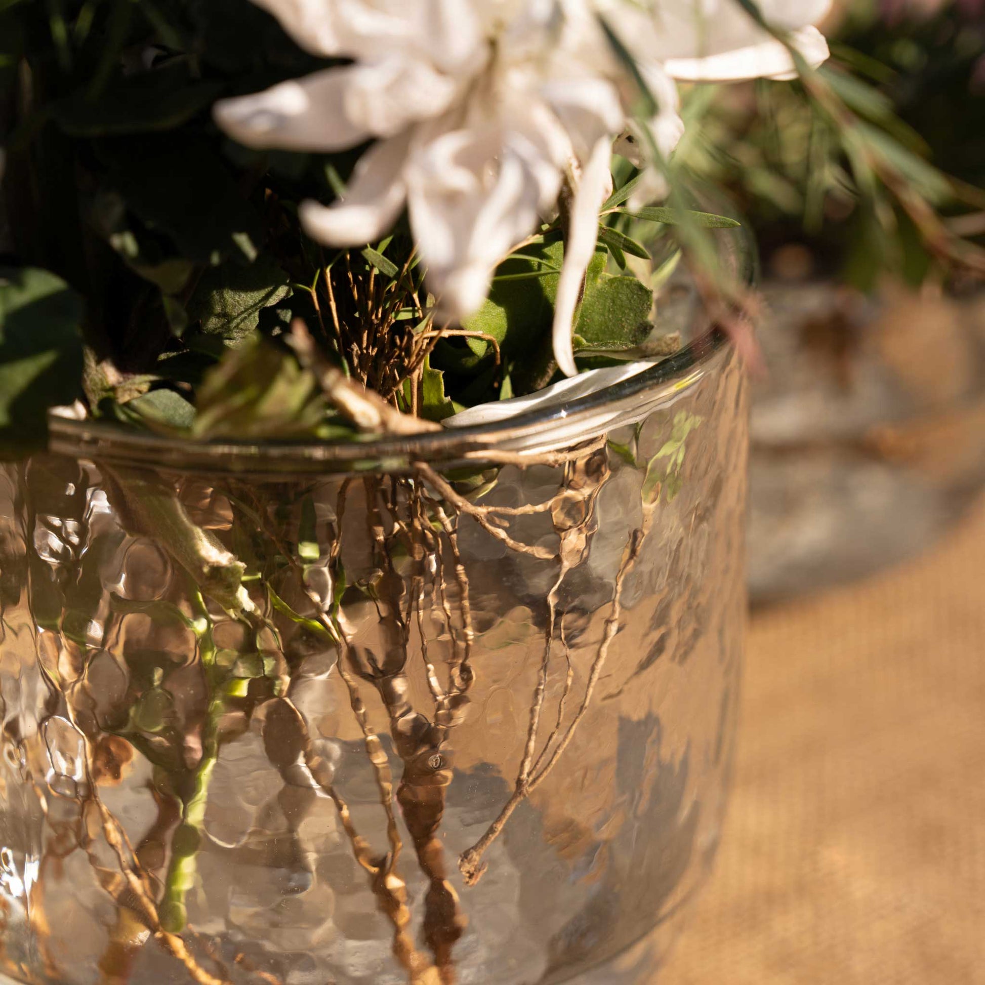 A close up of a floral bouquet using the collective pebbled vase and flower frog on a neutral background