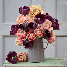Bouquet of flowers from the queen of the night and la belle epoque bundle in a metal pitcher on a wooden surface with a light gray background
