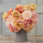 Bouquet of pink and yellow tulips from the double rose bundle in a gray vase on a wooden surface with a light gray background.