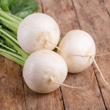 A vibrant, round, white Shogoin turnip with a smooth skin, captured close-up against a wooden background.