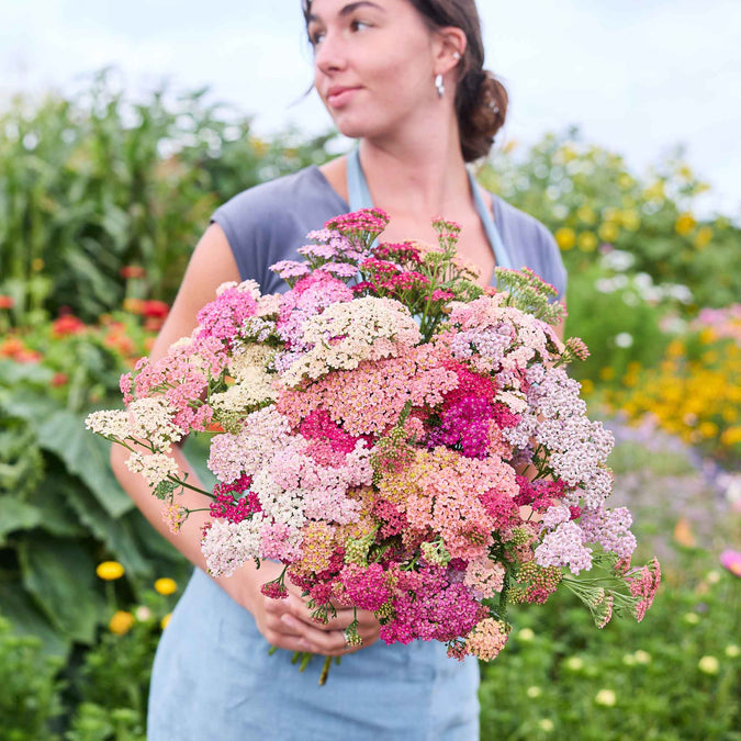Woman holding a bouquet of summer berries yarrow flowers in a garden setting