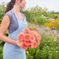 Bouquet of benary giant salmon rose zinnia flowers held by a person wearing a light blue dress.