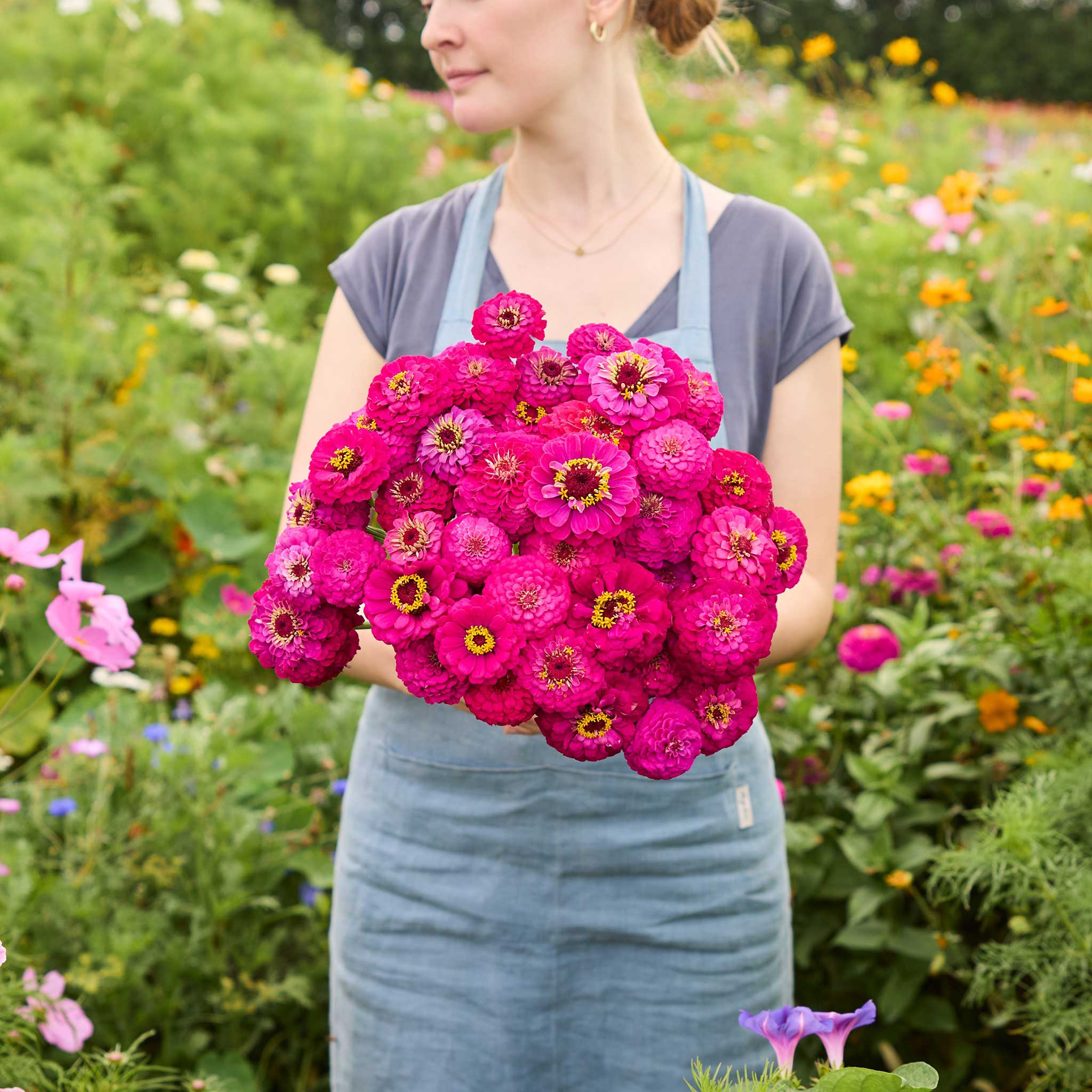 Person holding a bouquet of deep pink flowers from the zinnia oklahoma bundle in a natural setting