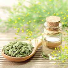 Close-up of fennel seeds with a wooden spoon on a white surface, ready for culinary use or planting.