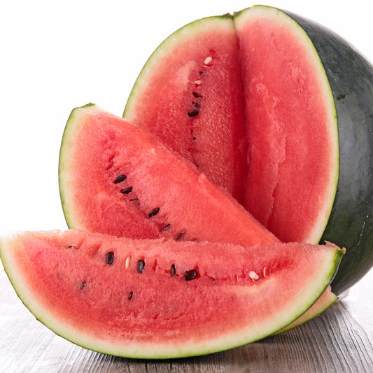 A dark green Sugar Baby watermelon sits on a wooden surface with a white background.